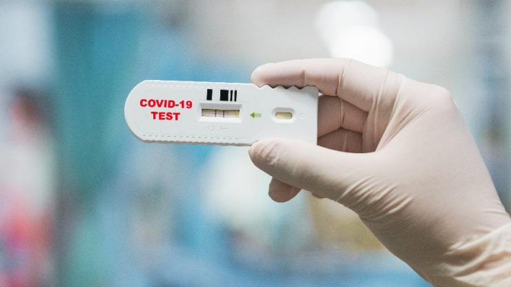 Mão de luva cirúrgica, segurando um teste rápido para Covid-19; dúvidas sobre coronavírus