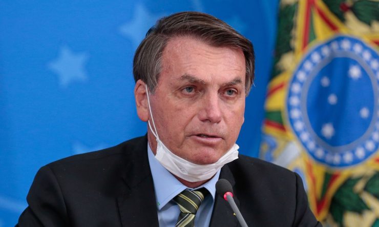 Jair Bolsonaro fazendo declaração à imprensa no Planalto. Ele usa máscara no pescoço. Não existem provas que enxofre protege contra coronavírus